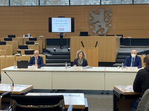 Birgit Keller, Herrmann Binkert und der TLMB auf dem Podium im Plenarsaal des Landtags. Klick öffnet eine vergrößerte Ansicht.