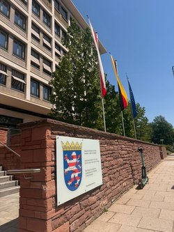 Sitz des Beauftragten, Aussenansicht am Eingang zu Verwaltungsgebäuden der Hessischen Landesregierung. Hausfassade und Mauervorsprung mit Landeswappen. Klick öffnet eine vergrößerte Ansicht.