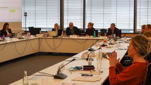 Mitglieder der AG 8 bei ihrer Tagung in einem Sitzungssaal des Thüringer Landtags. Im Bild: Präsidium mit Moderator und u-förmige Tischreihe mit Gremienmitgliedern.