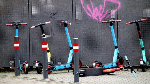 blaue E-Scooter in Reihe auf Gehweg geparkt 