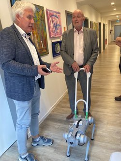 Prof. Groß im Gespräch mit TLMB Leibiger, der den Robo-Dog am Geschirr führt. Klick öffnet eine vergrößerte Ansicht.