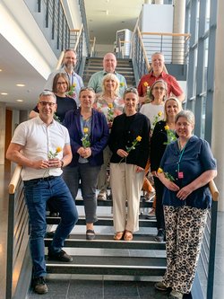 Gruppenbild der Beraterinnen und Berater auf einer Treppe im Landtag stehend, nach der Ernennung mit gelben Rosen in der Hand. Klick öffnet eine vergrößerte Ansicht.