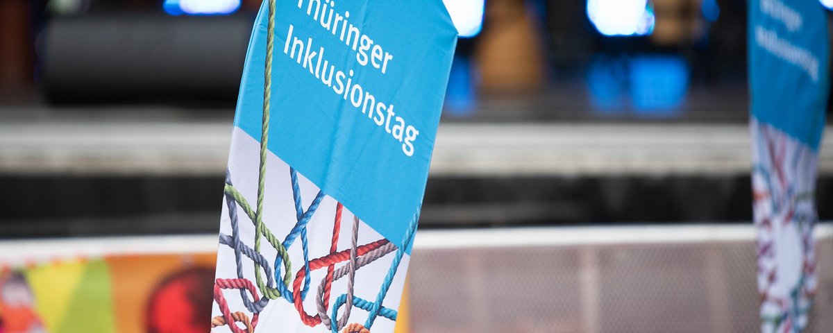 Beachflag mit der Aufschrift "Thüringer Inklusionstag" vor der Bühne, auf welcher der Inklusionspreis vergeben wurdeBild: Melanie Kahl