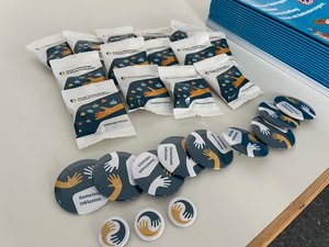 Werbeartikel des TLMB (Tüten mit Gummibärchen, Pins etc.) auf einem Messetisch