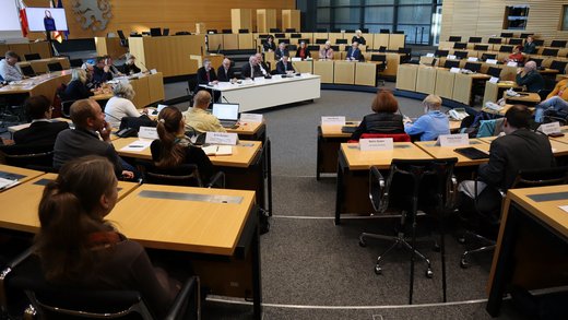 Blick in den Plenarsaal, auf den Plätzen sitzen Mitglieder des LBB, in der Mitte des Saals steht das Podium mit den Referenten