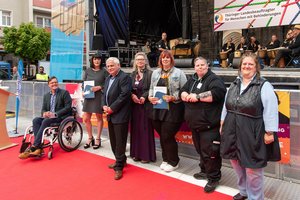 Fünfköpfige Jury aus Mitgliedern des Landesbehindertenbeirats mit den Gewinnern der Anerkennungspreise. Klick öffnet eine vergrößerte Ansicht.